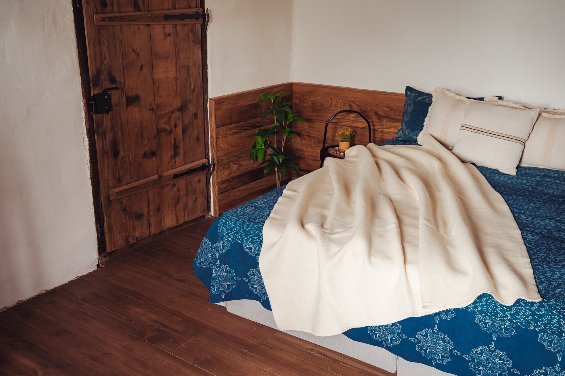 Handwoven Merino wool throw on bed with blue bedspread, showcasing natural color and craftsmanship.