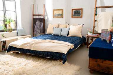 Handwoven bed cover made from organic hemp with indigo dyeing, displayed in a rustic bedroom setting.