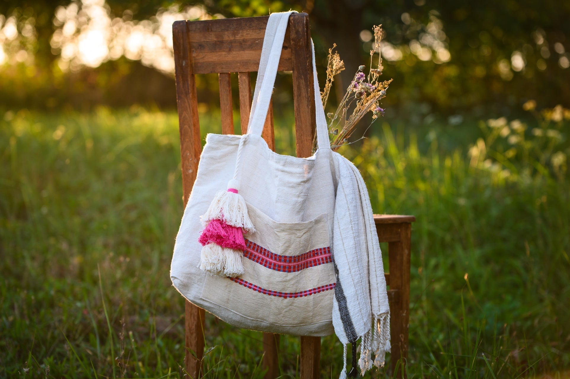 Antique Hungarian grainsack tote bag made from handwoven organic hemp, displayed on a wooden chair outdoors.