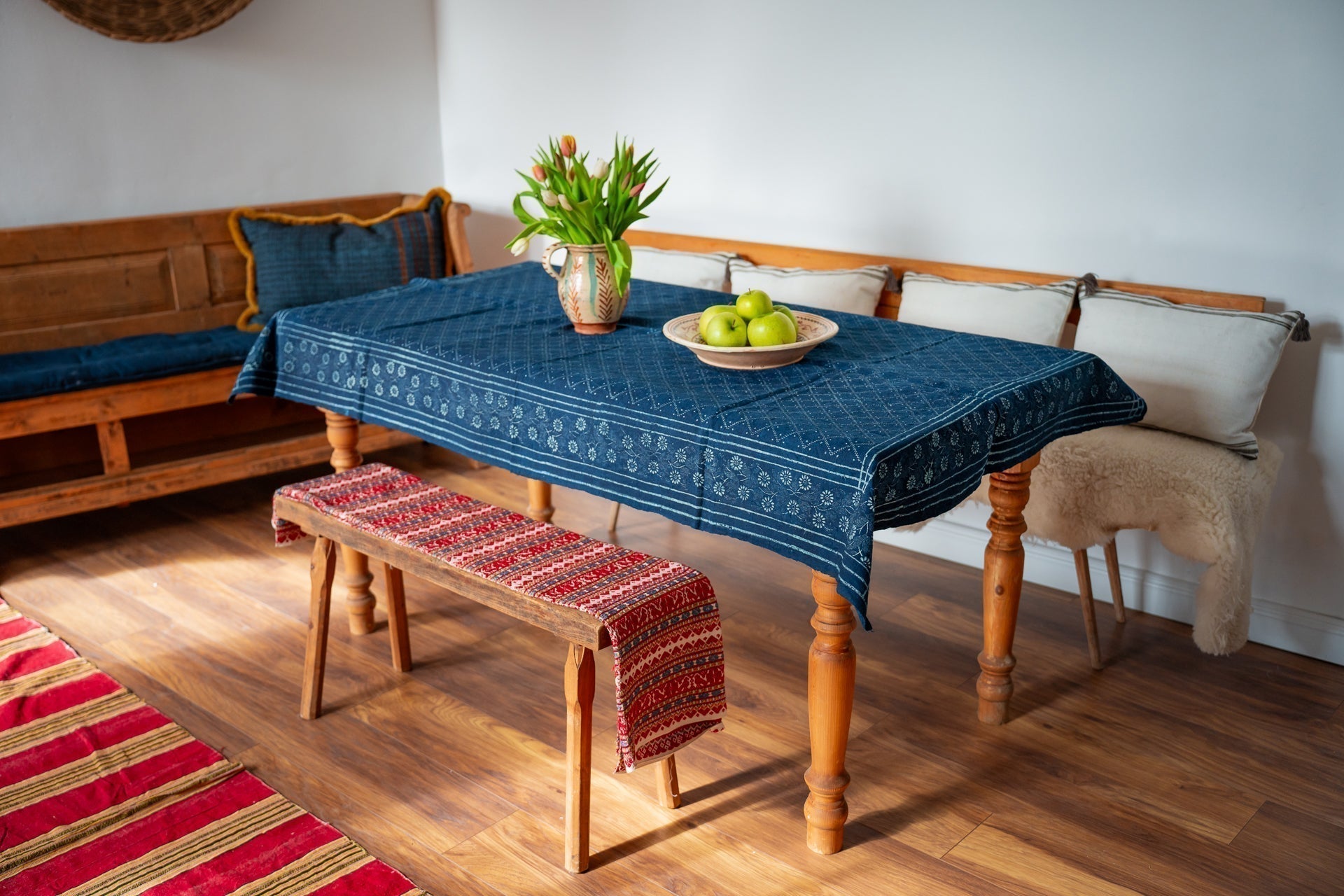 Antique handwoven Hungarian hemp table cloth with indigo dye and heritage patterns on wooden table.