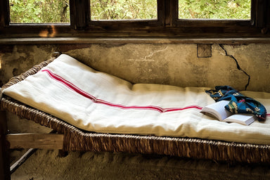 Antique handwoven Hungarian grain sack bedroll with cotton fill on rustic bed.