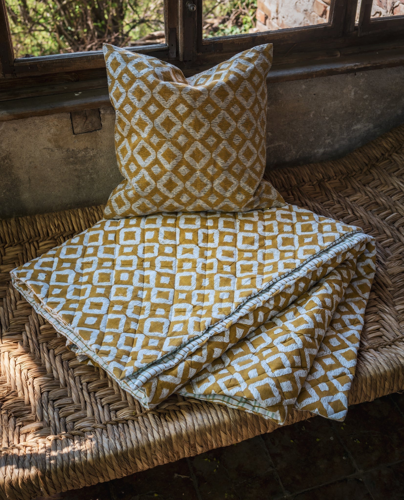 Hand printed linen pillow on rustic woven surface, featuring geometric pattern with Earthy tones.
