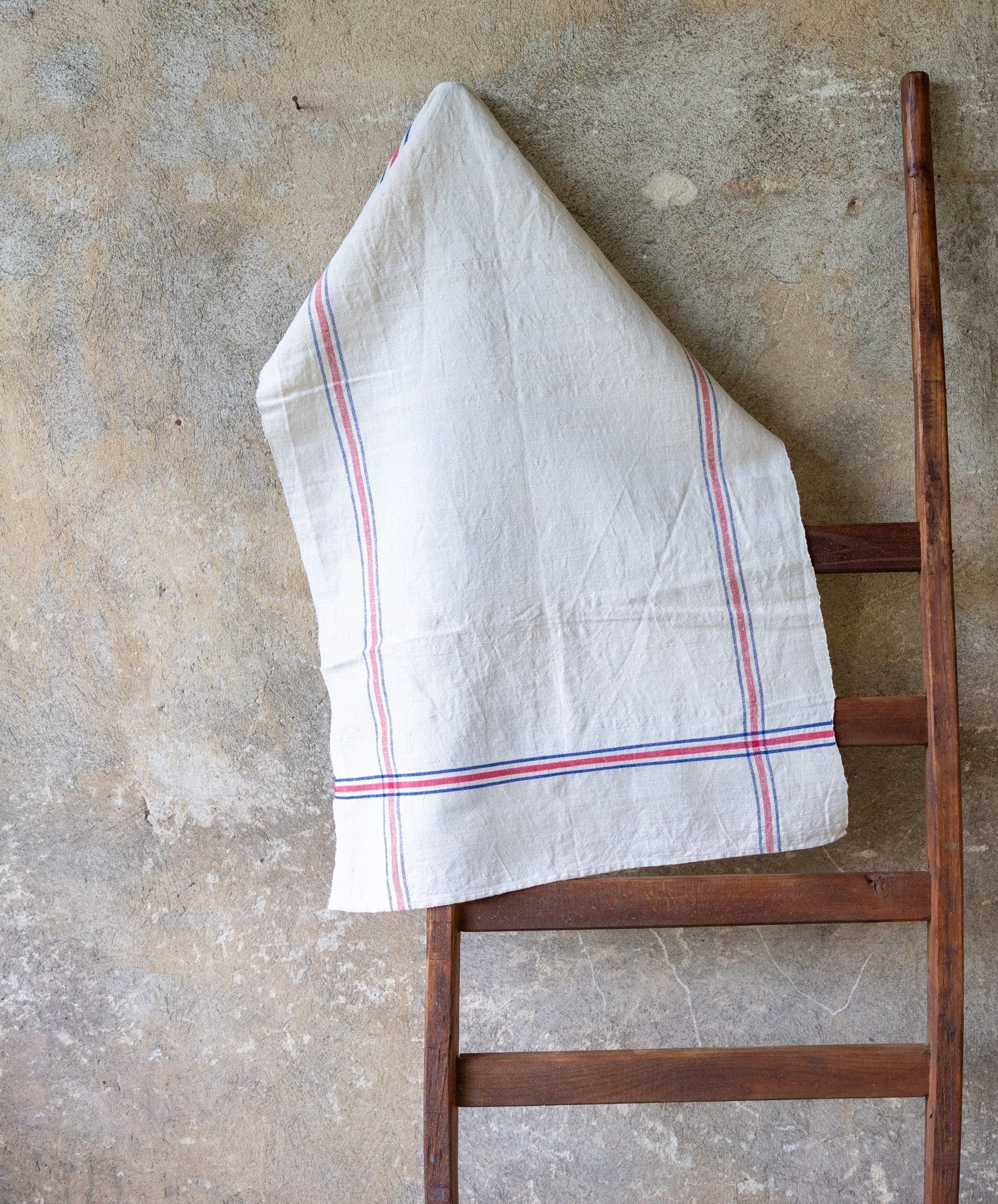 Handwoven antique Hungarian hemp towel hanging on a wooden ladder.