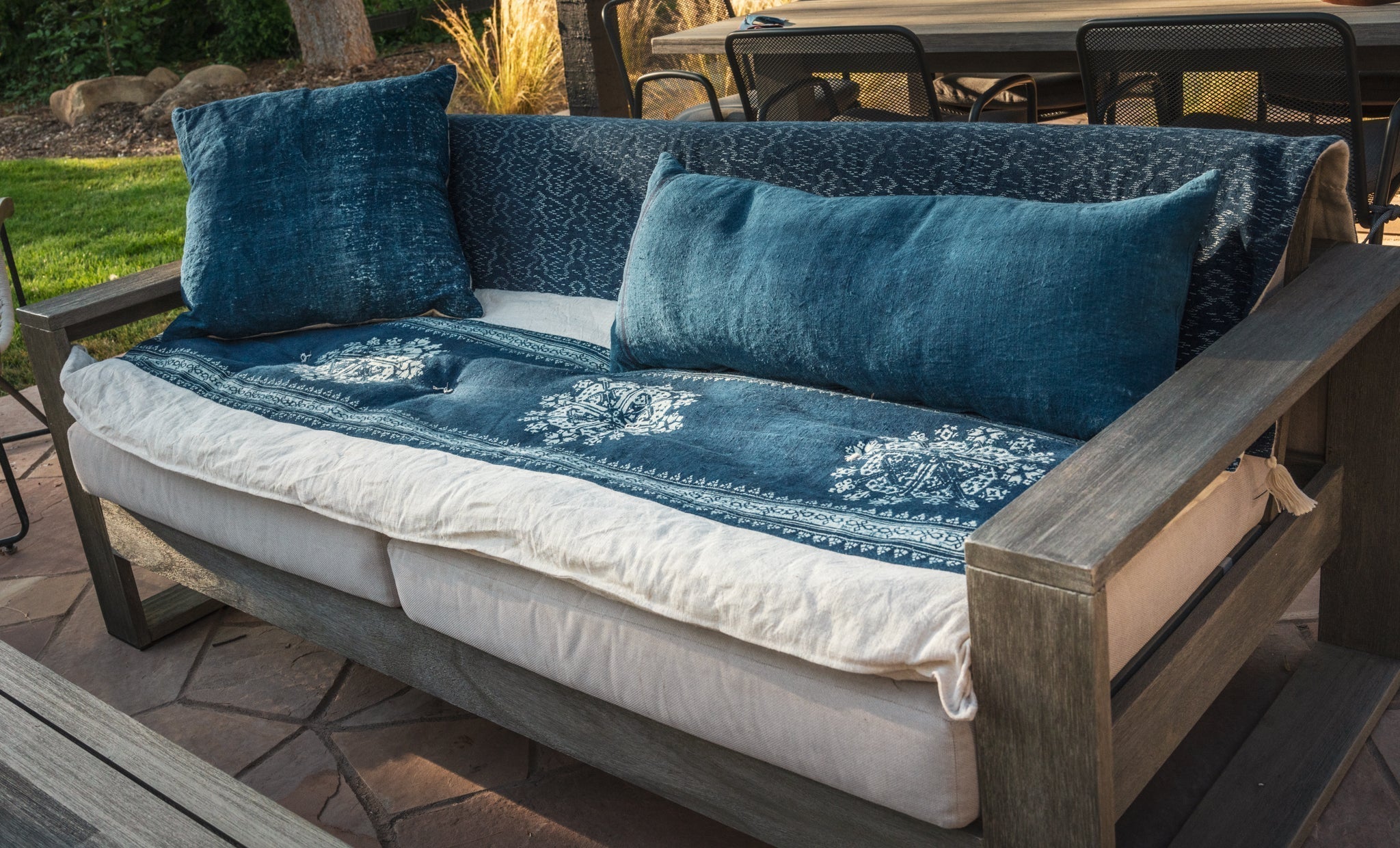 Antique handwoven hemp bedroll with indigo dye pattern on outdoor sofa.