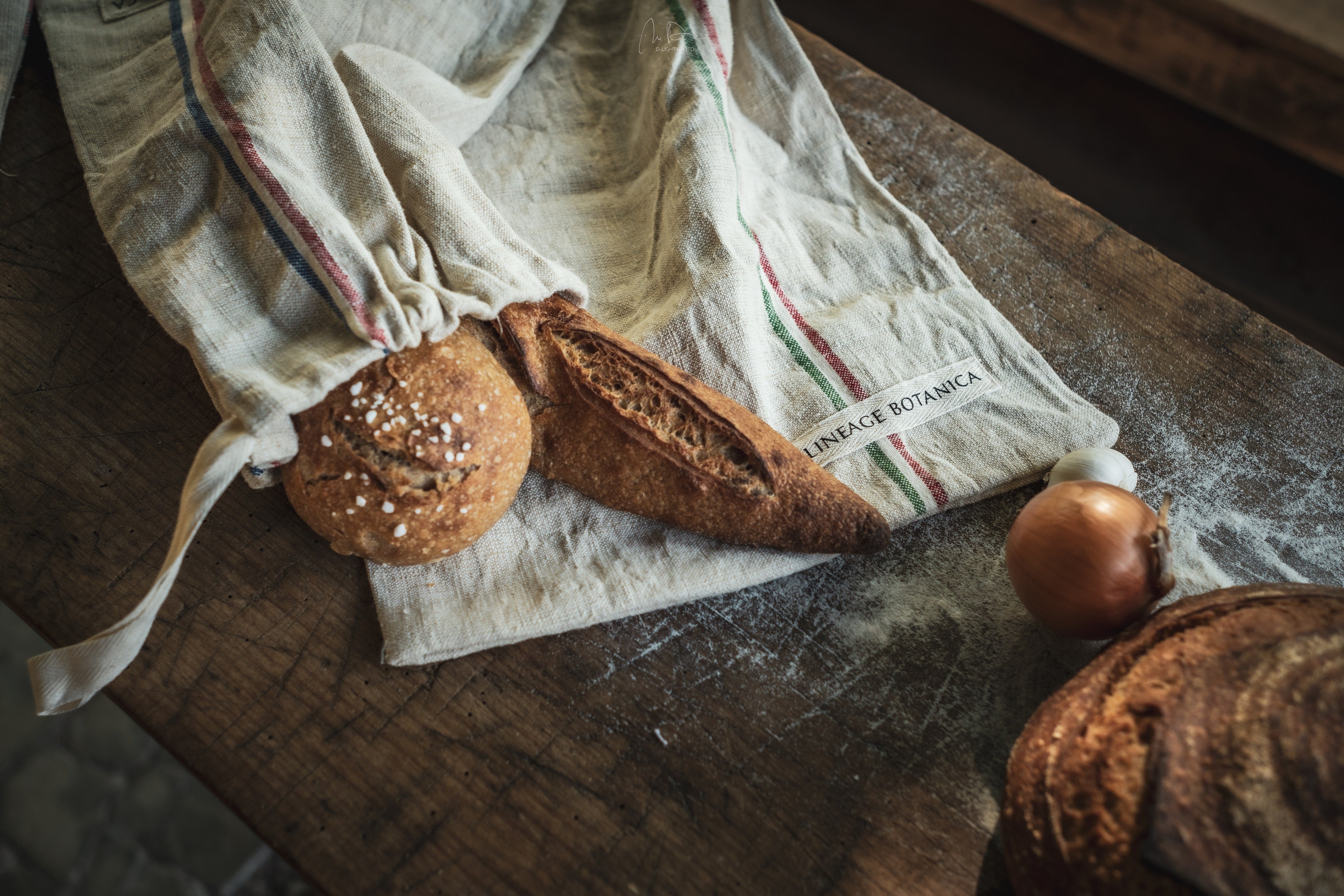 Handwoven antique hemp bread bags with loaves on a wooden table.