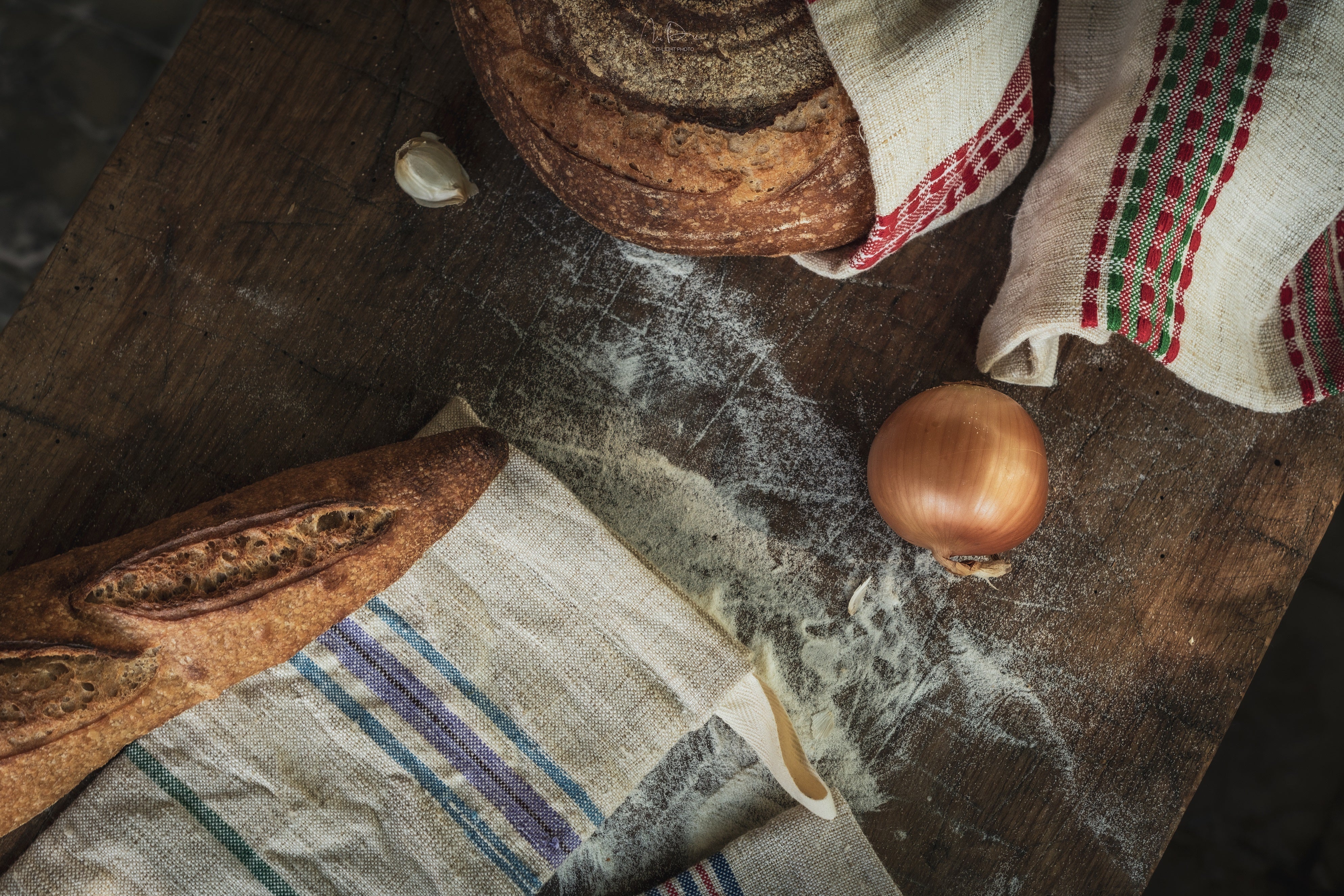 Handwoven antique hemp bread bags on a wooden table with bread and onion.