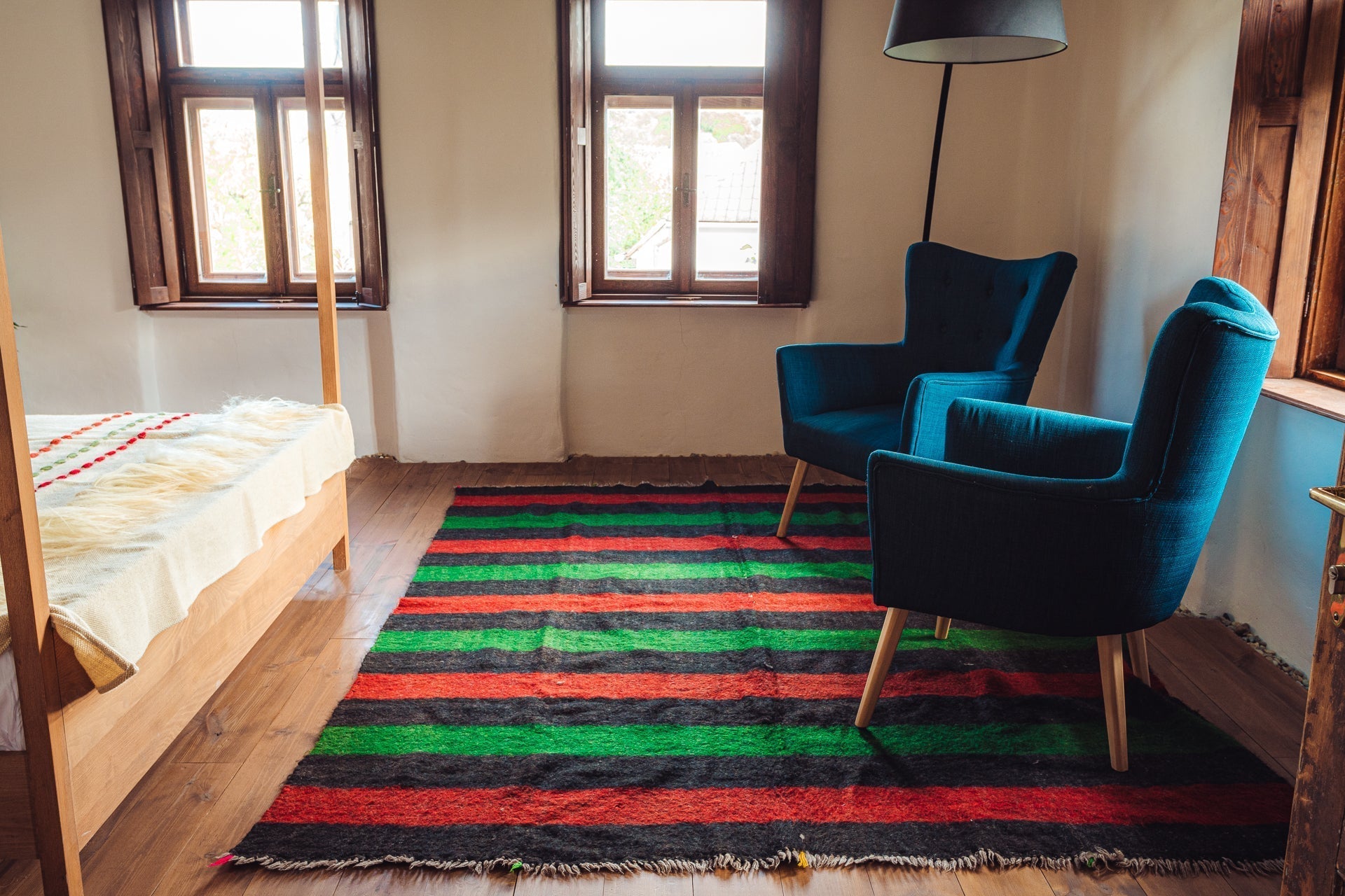 Antique handwoven Bulgarian rug with colorful stripes, 210x260 cm, displayed in a cozy room with wooden floors and rustic furniture.