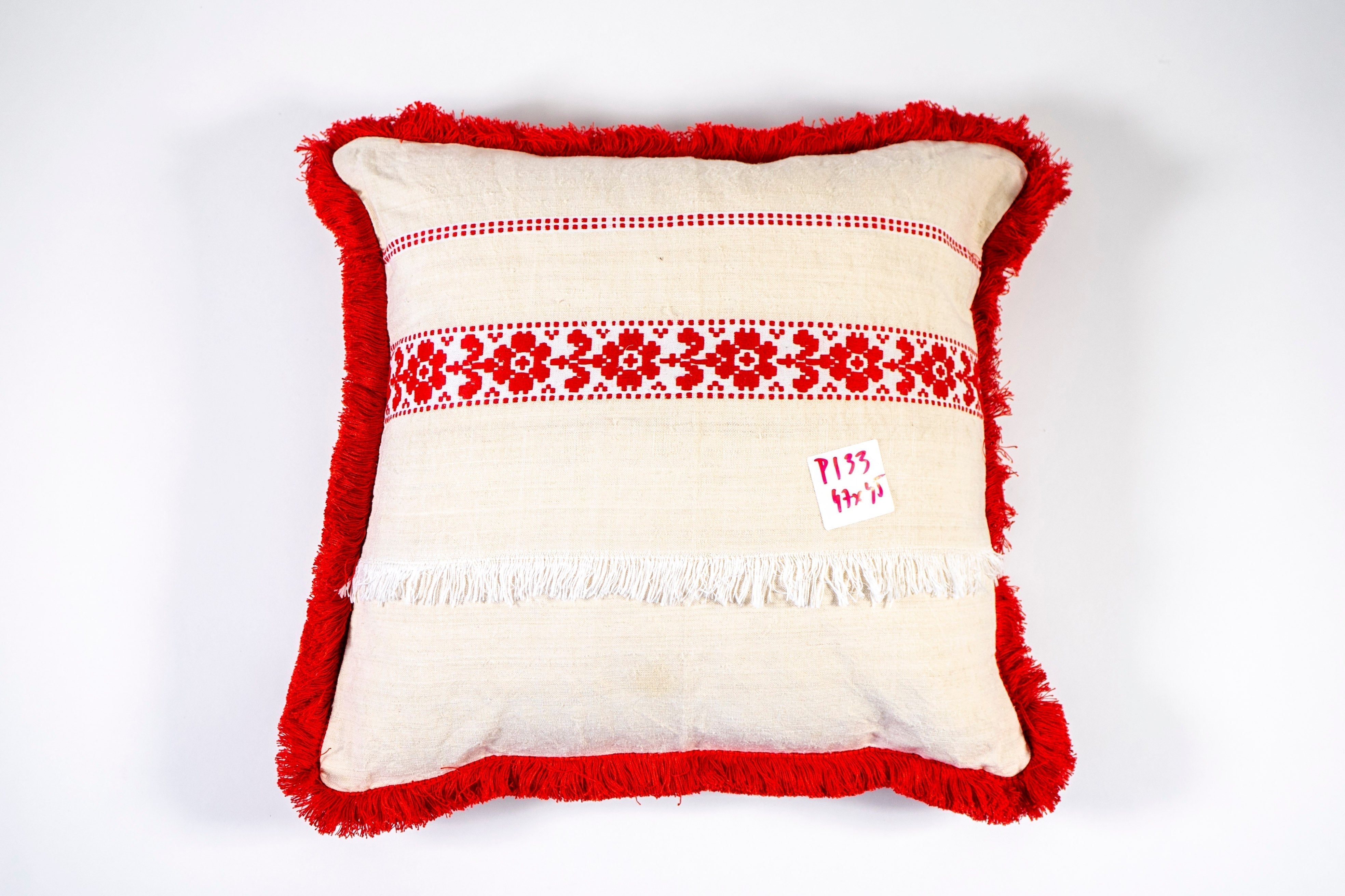 Embroidered antique handwoven Hungarian hemp pillow with red fringe.