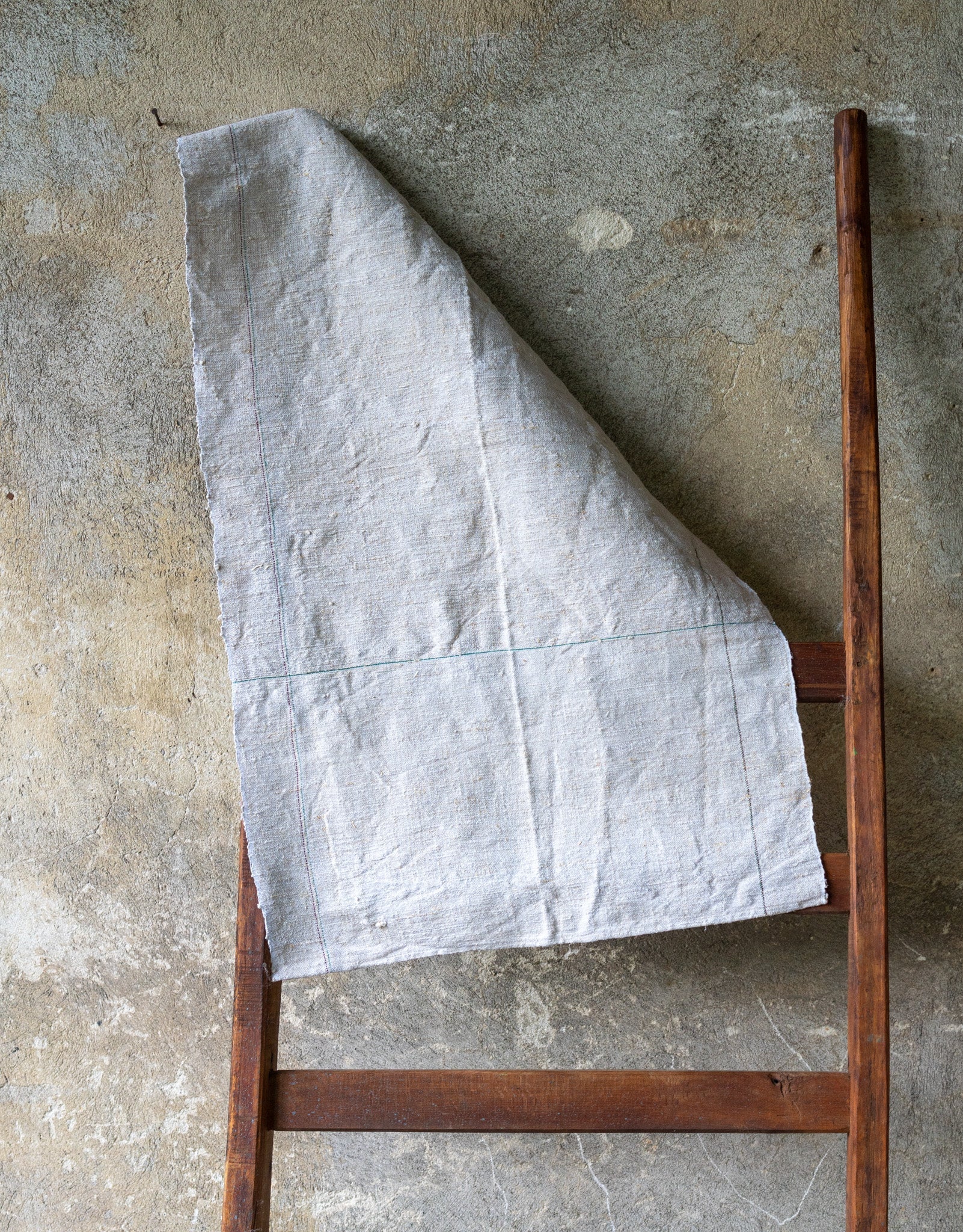 Handwoven antique Hungarian hemp towel on wooden ladder.