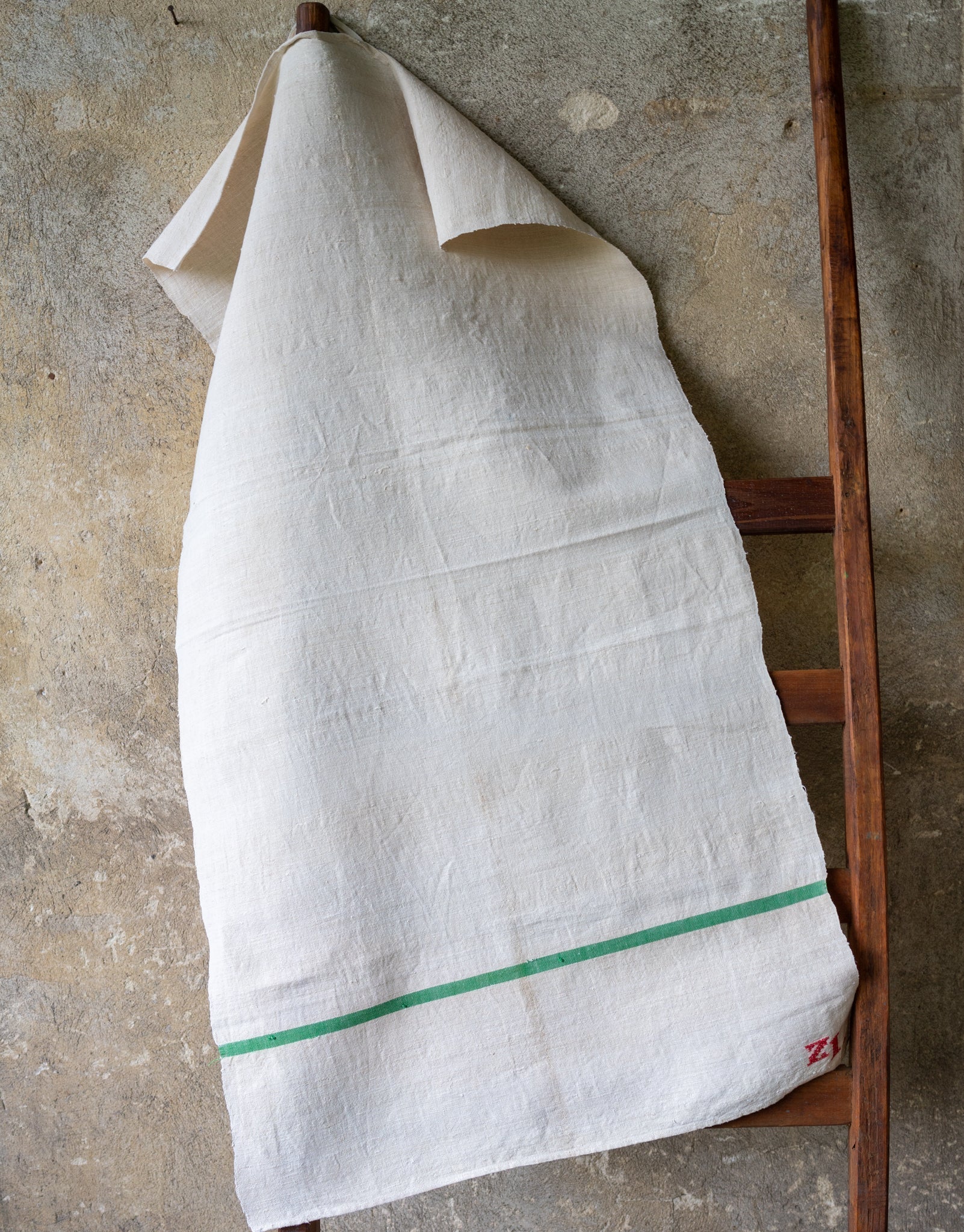 Handwoven antique Hungarian hemp towel on wooden ladder.