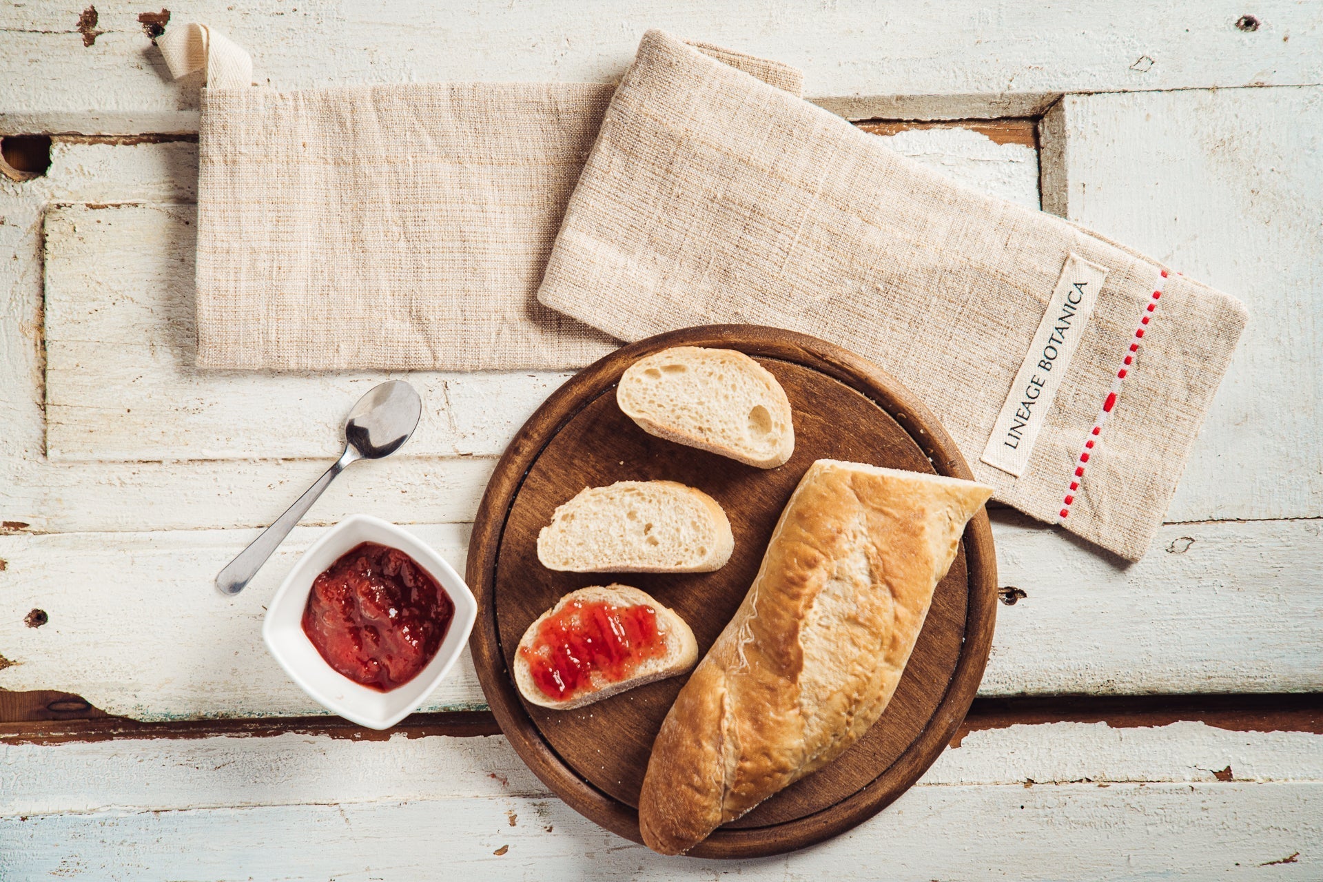 Handwoven antique hemp baguette bag with bread and jam on a rustic table.