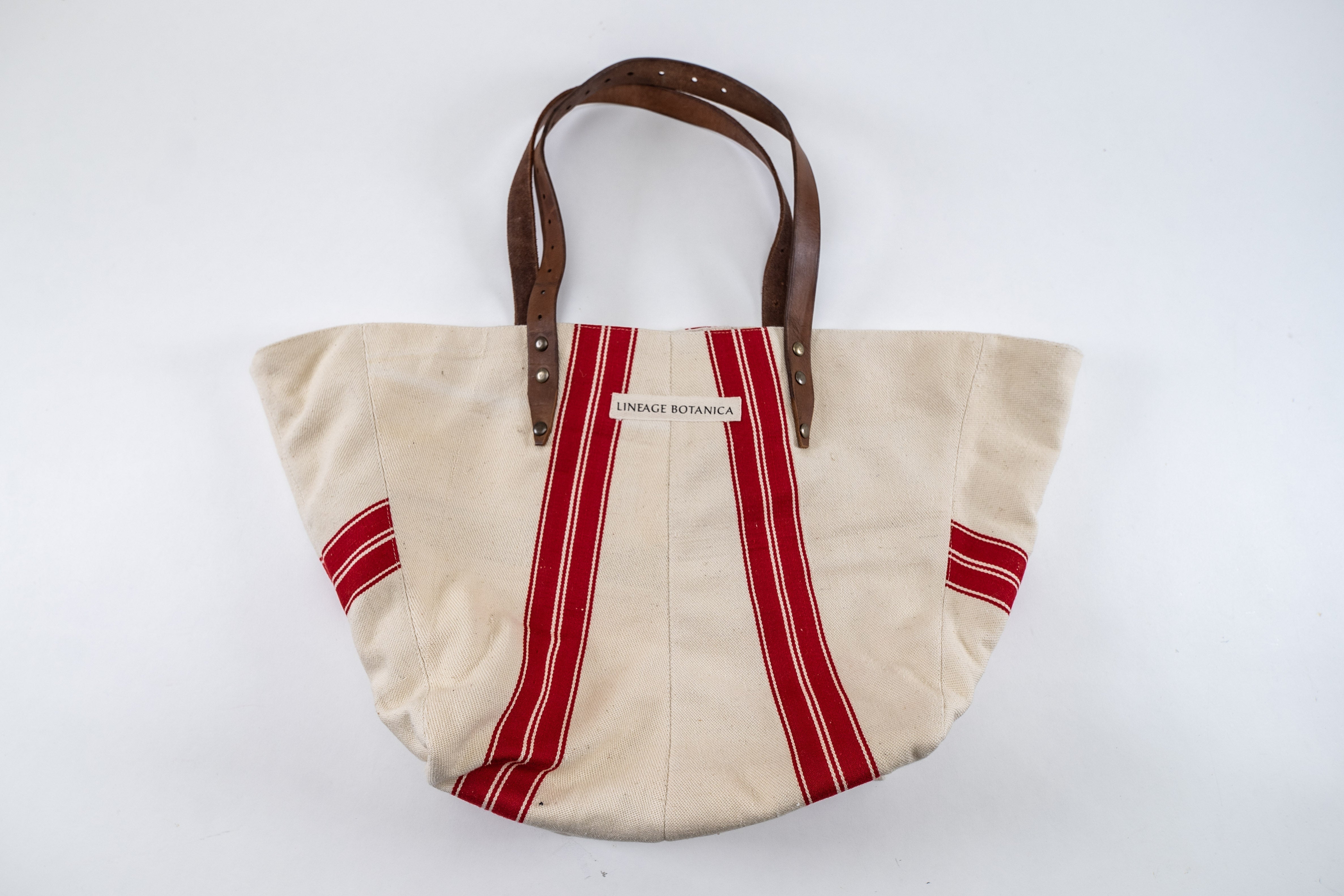 Handwoven antique Hungarian hemp bag with red stripes and leather handles.