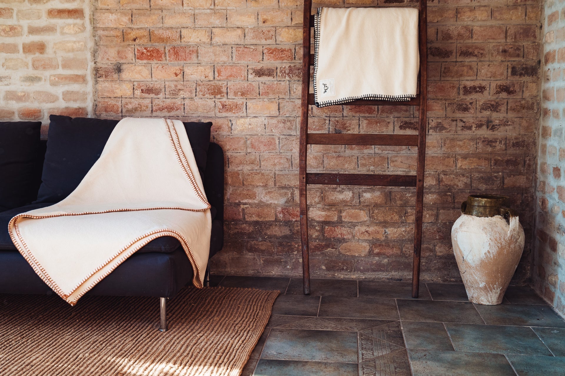 Eco-cotton throw with hand-stitched cinnamon trim on sofa, showcasing luxurious softness.