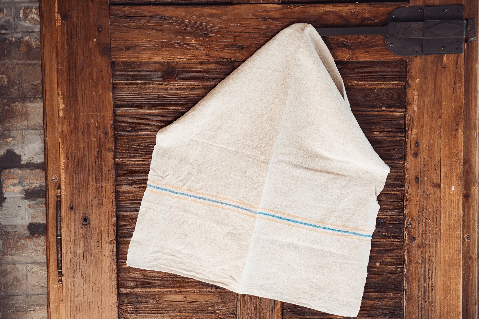 Handwoven antique Hungarian hemp towel hanging on a wooden door.