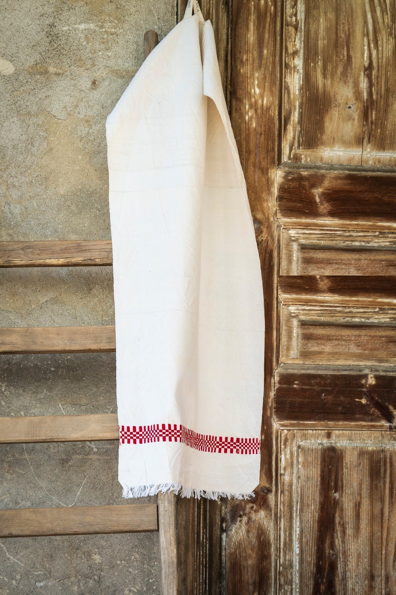 Handwoven antique Hungarian hemp towel hanging on wooden door.