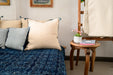 Handwoven antique hemp pillow with handstitching on a blue patterned bedspread, sustainable home decor accent.