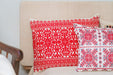 Embroidered handwoven Hungarian hemp pillows with red patterns on a neutral background.