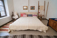 Embroidered handwoven antique Hungarian hemp pillows on a bed with colorful designs and cozy setting.