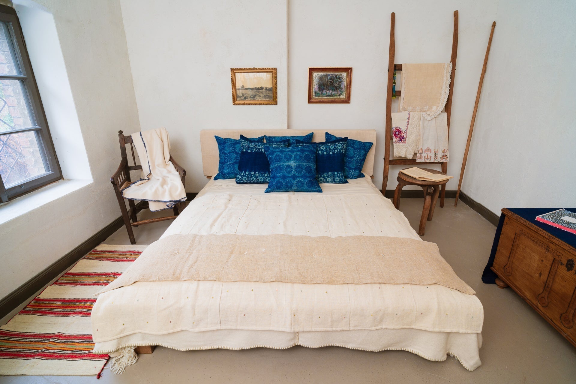 Handwoven antique Hungarian hemp pillow with indigo design on bed in cozy room.