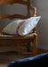 Handwoven antique Hungarian hemp pillow on rustic wooden chair.