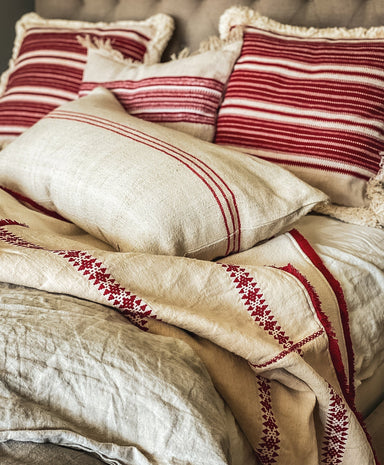 antique Hungarian hemp throw with red embroidery and eco-cotton backing on bed with matching pillows