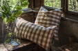 Handwoven cotton pillow with natural plant dye by a window.