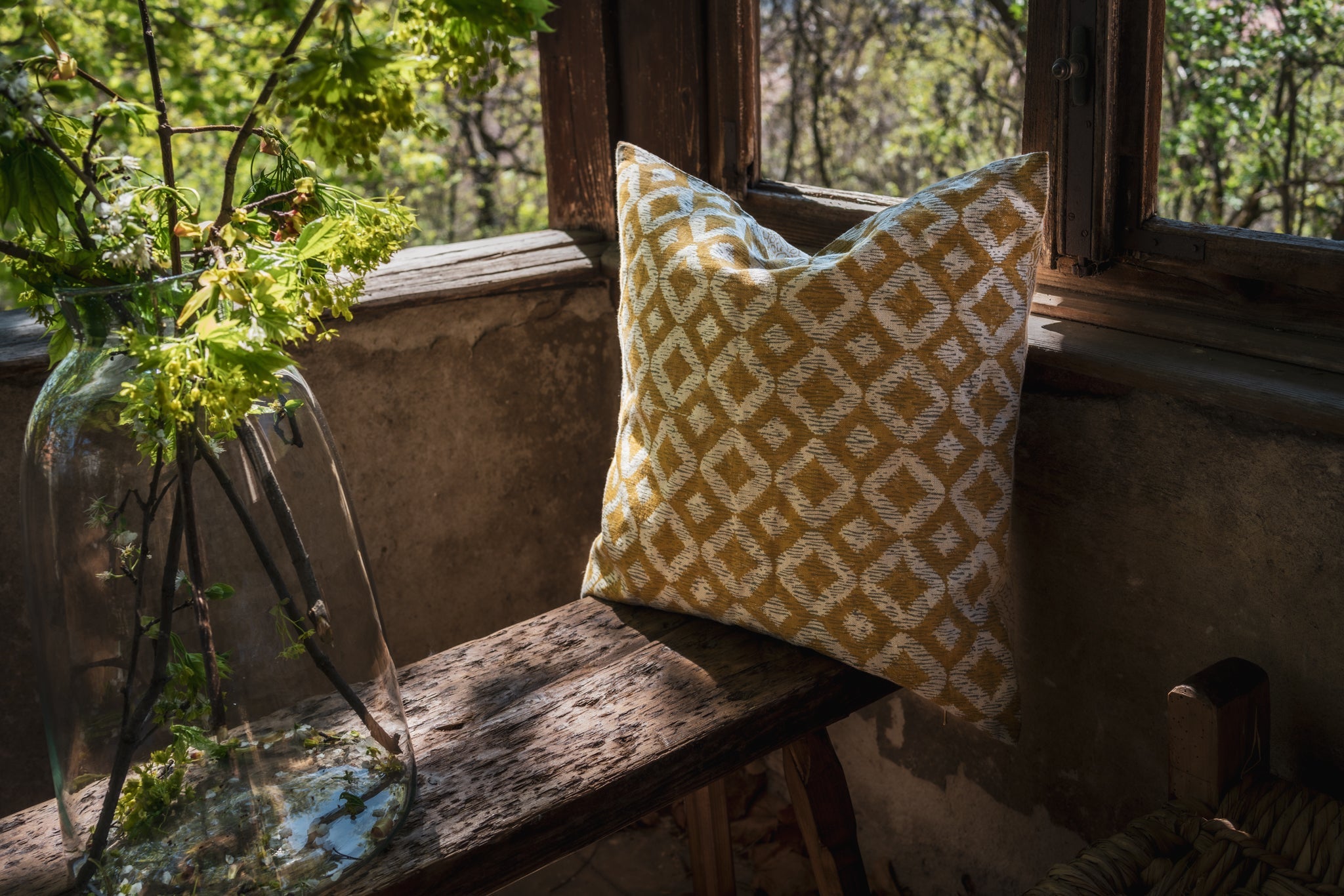 Hand printed linen pillow with geometric design on rustic wooden bench.