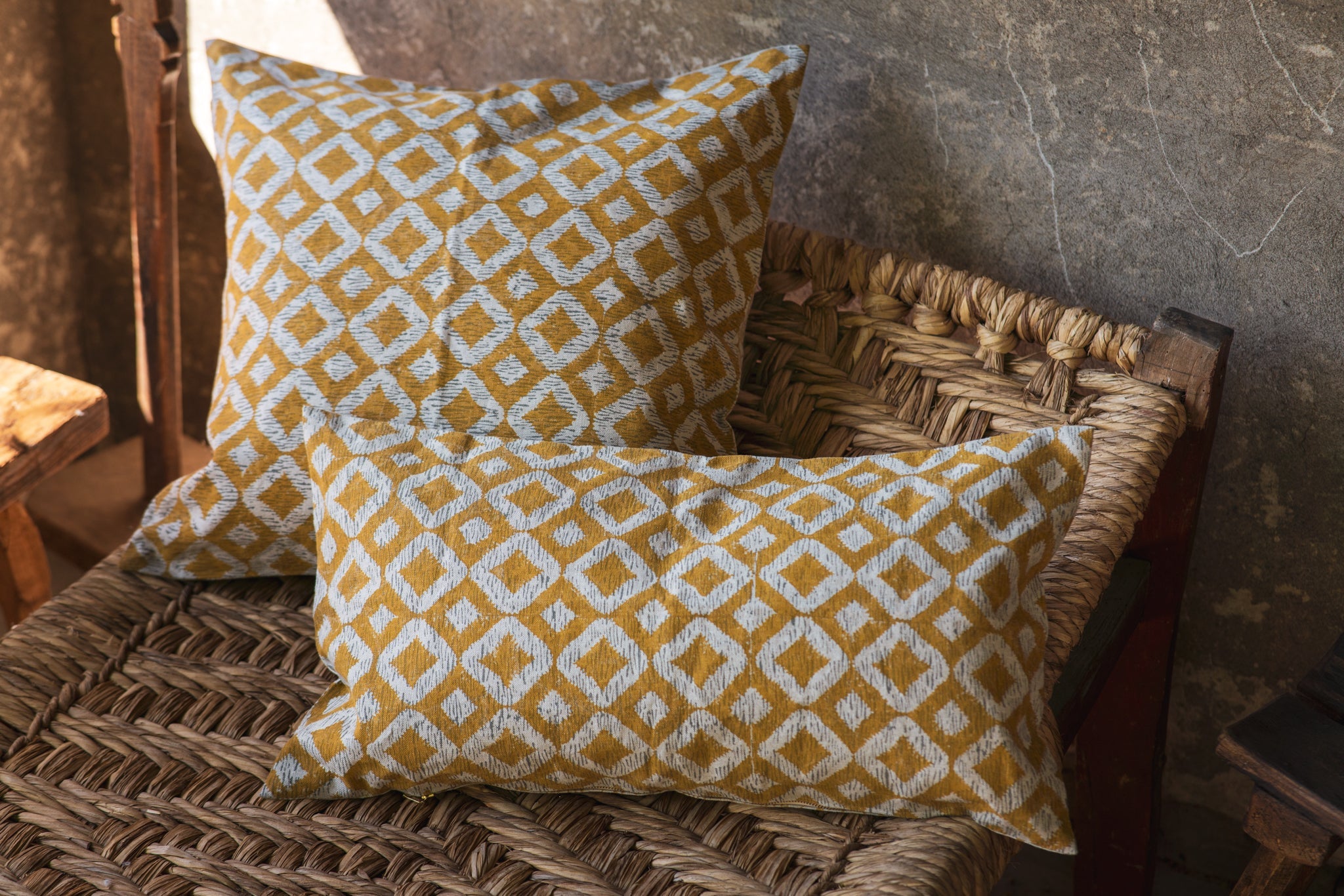 Hand printed linen pillows with geometric patterns on a woven chair.