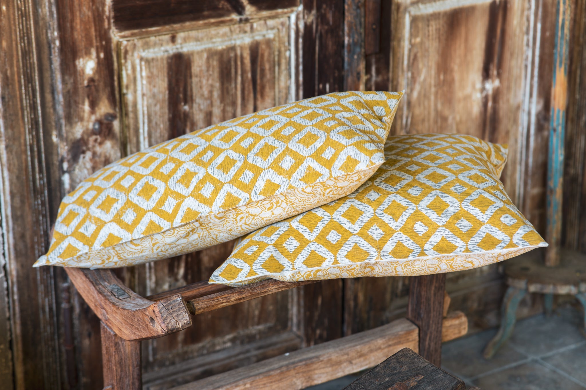 Hand printed linen pillow on rustic chair, artisan made in India.