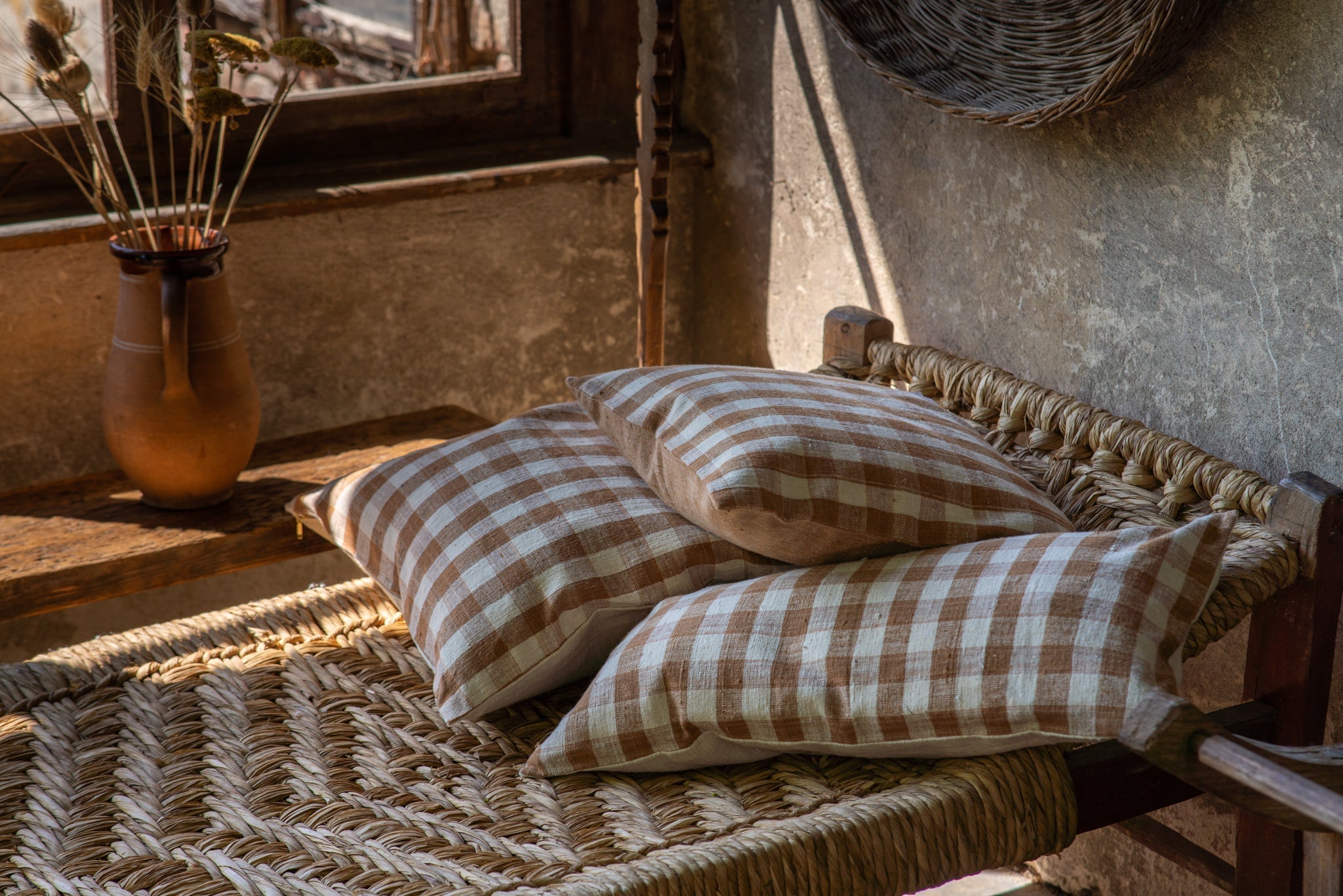 Handwoven organic cotton pillows on rustic woven bench, with natural plant dye and unique patterns for home decor accents.