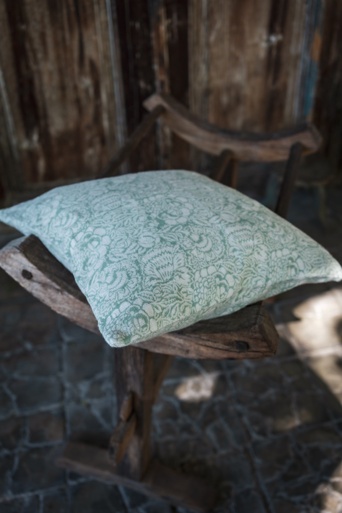 Hand block printed linen pillow with heritage design on wooden chair.