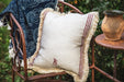 Antique handwoven decorative Hungarian hemp pillow on chair outdoors.