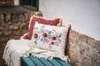 Handwoven antique Hungarian hemp pillow with floral embroidery on a rustic bench.