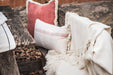 Grain sack handwoven Hungarian hemp pillow with decorative fringing on rustic bench.