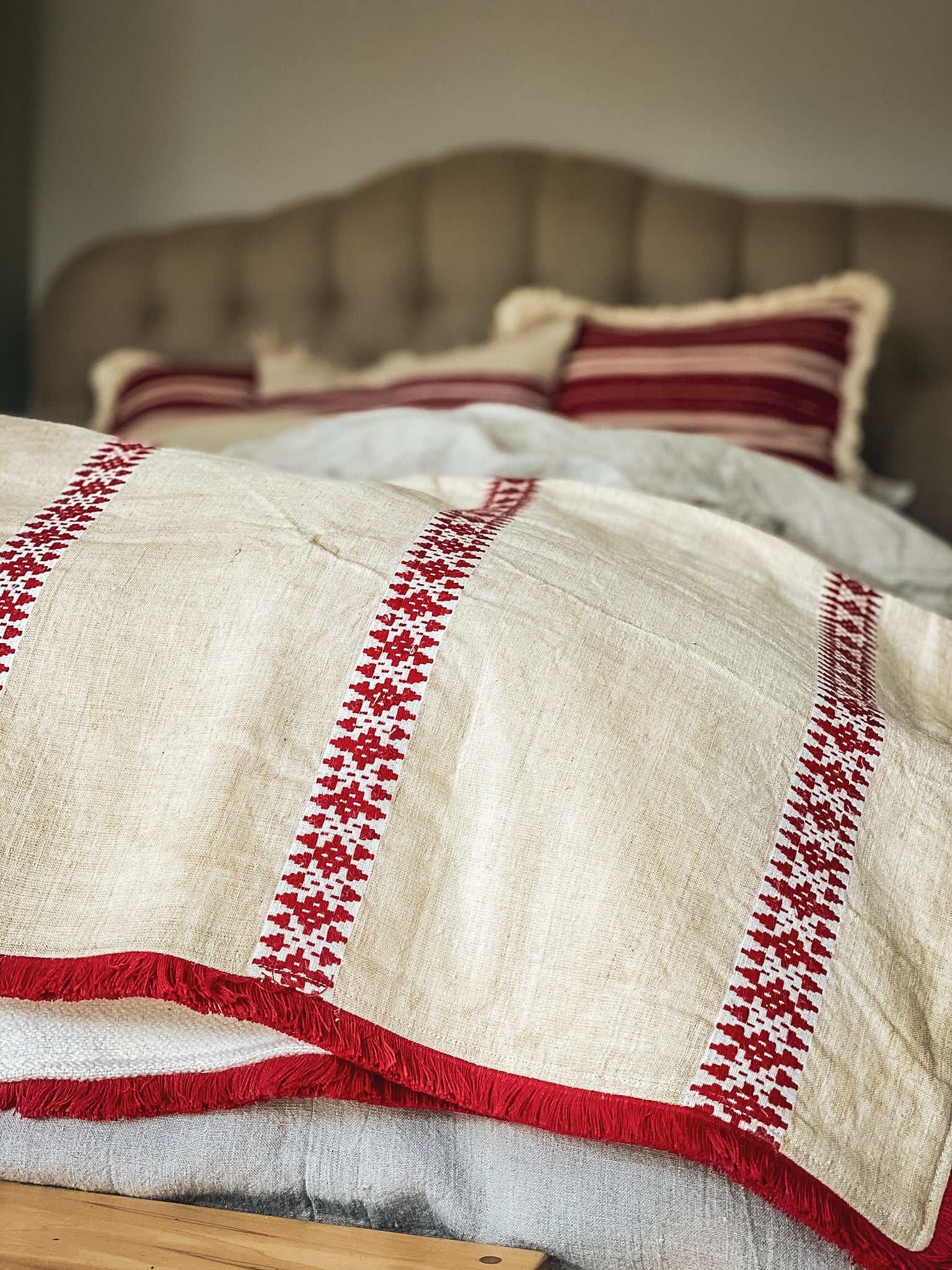 antique Hungarian hemp throw with red embroidered stripes and fringe on bed
