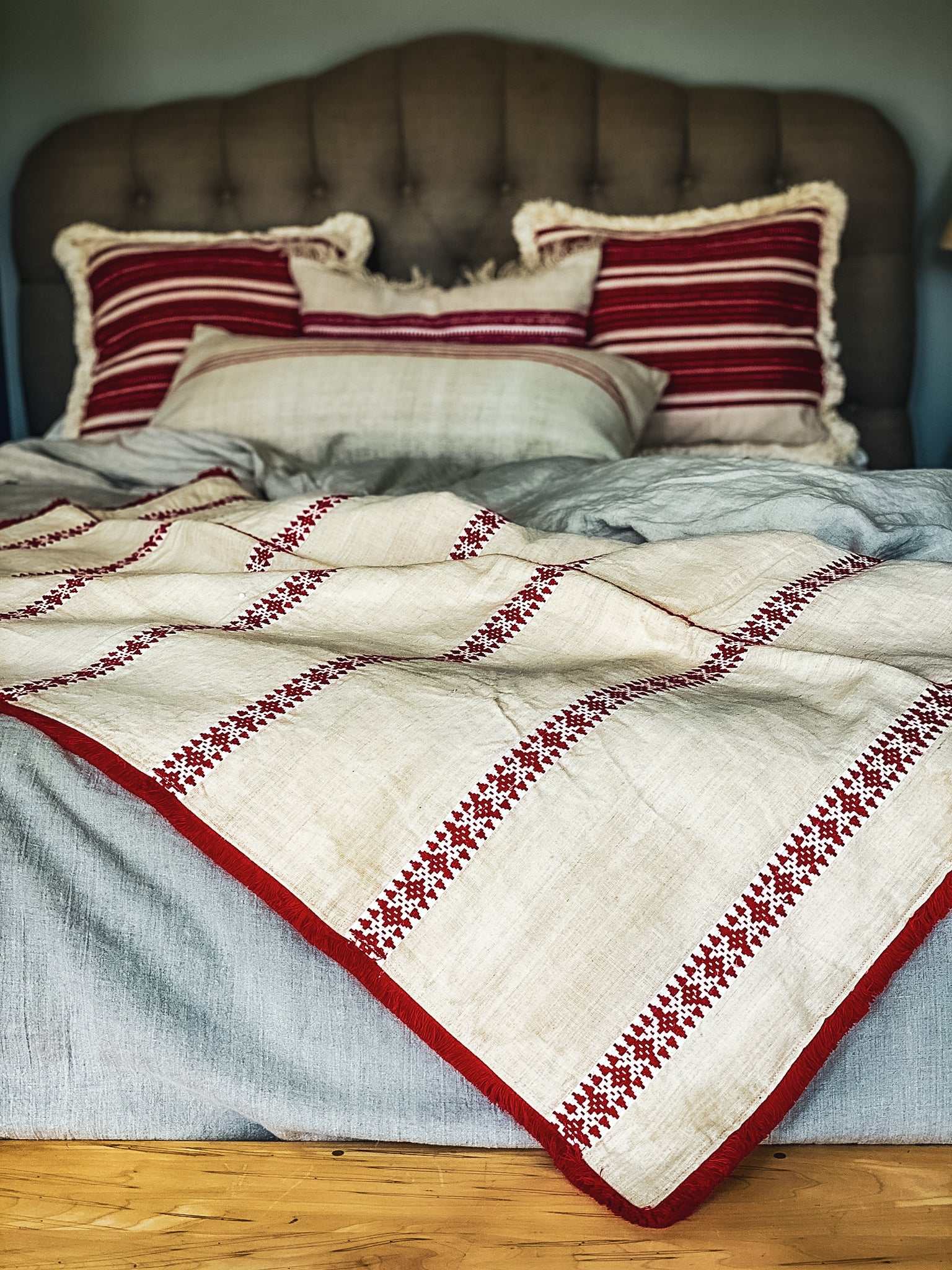 Antique Hungarian hemp throw with red embroidery on bed layered with pillows