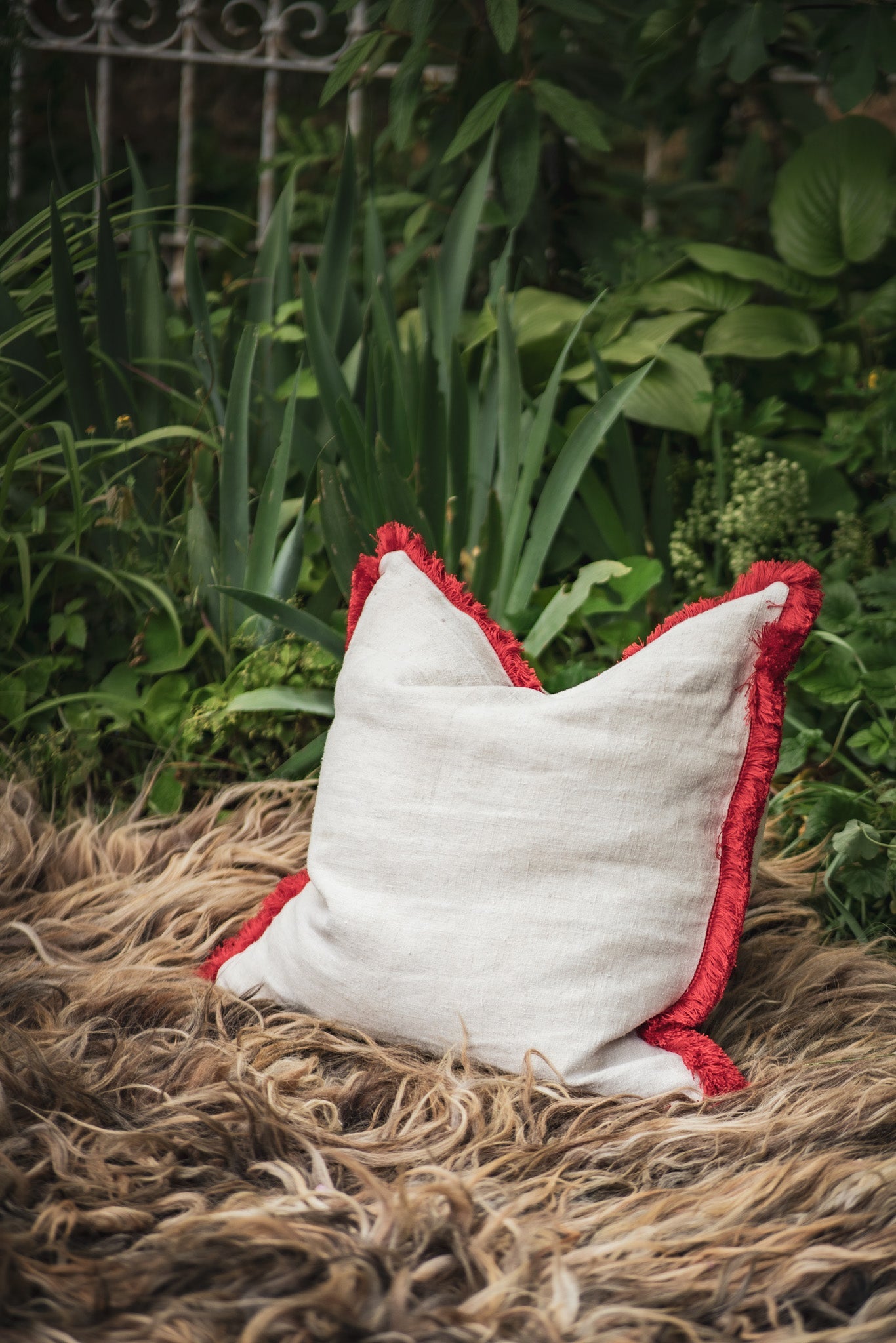 Handwoven antique Hungarian hemp pillow with red cotton fringe and metal zipper, featuring recycled goose down insert.