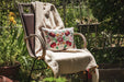 Embroidered handwoven antique Hungarian hemp pillow on chair in garden setting.