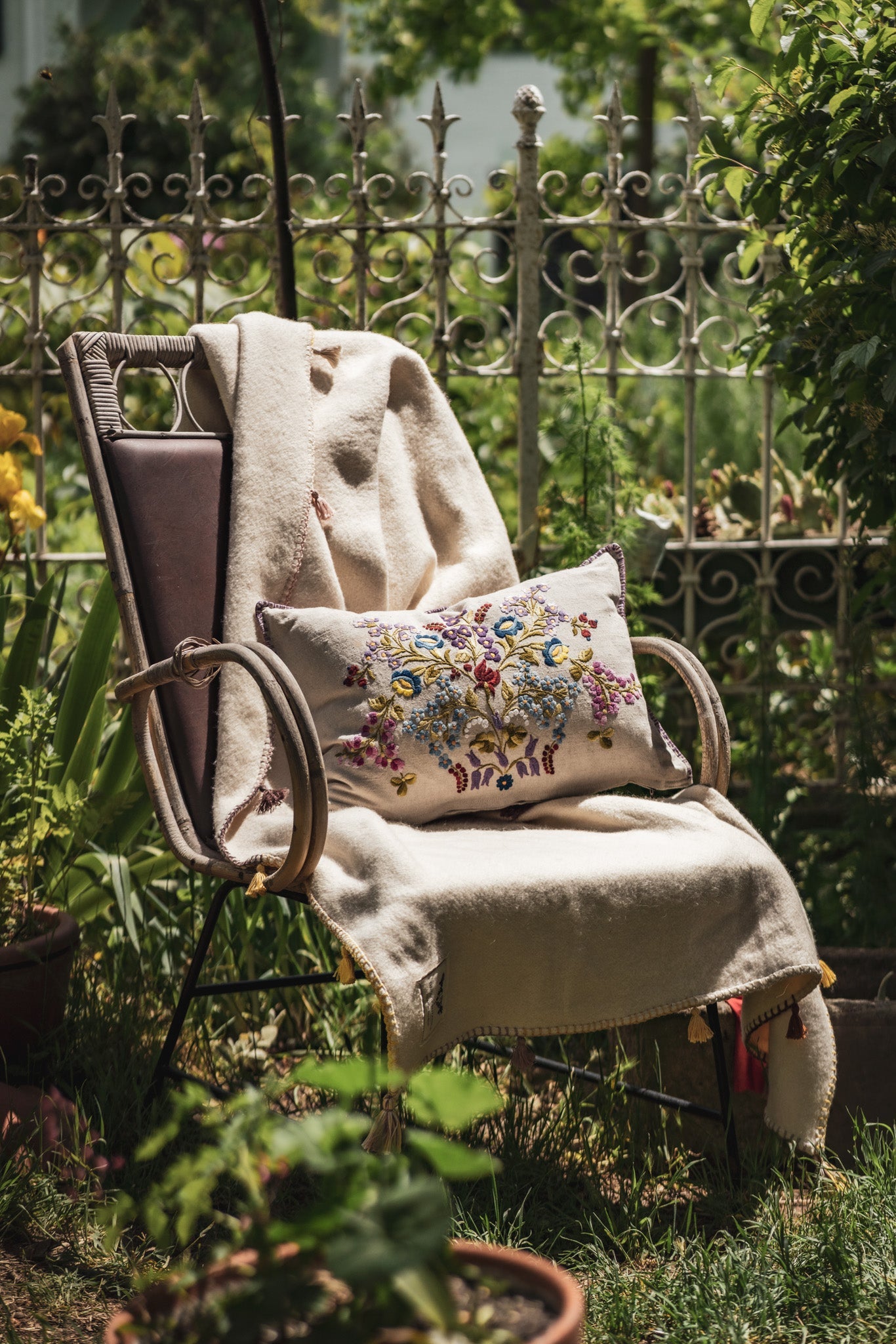 Embroidered handwoven antique Hungarian hemp pillow on chair in garden.