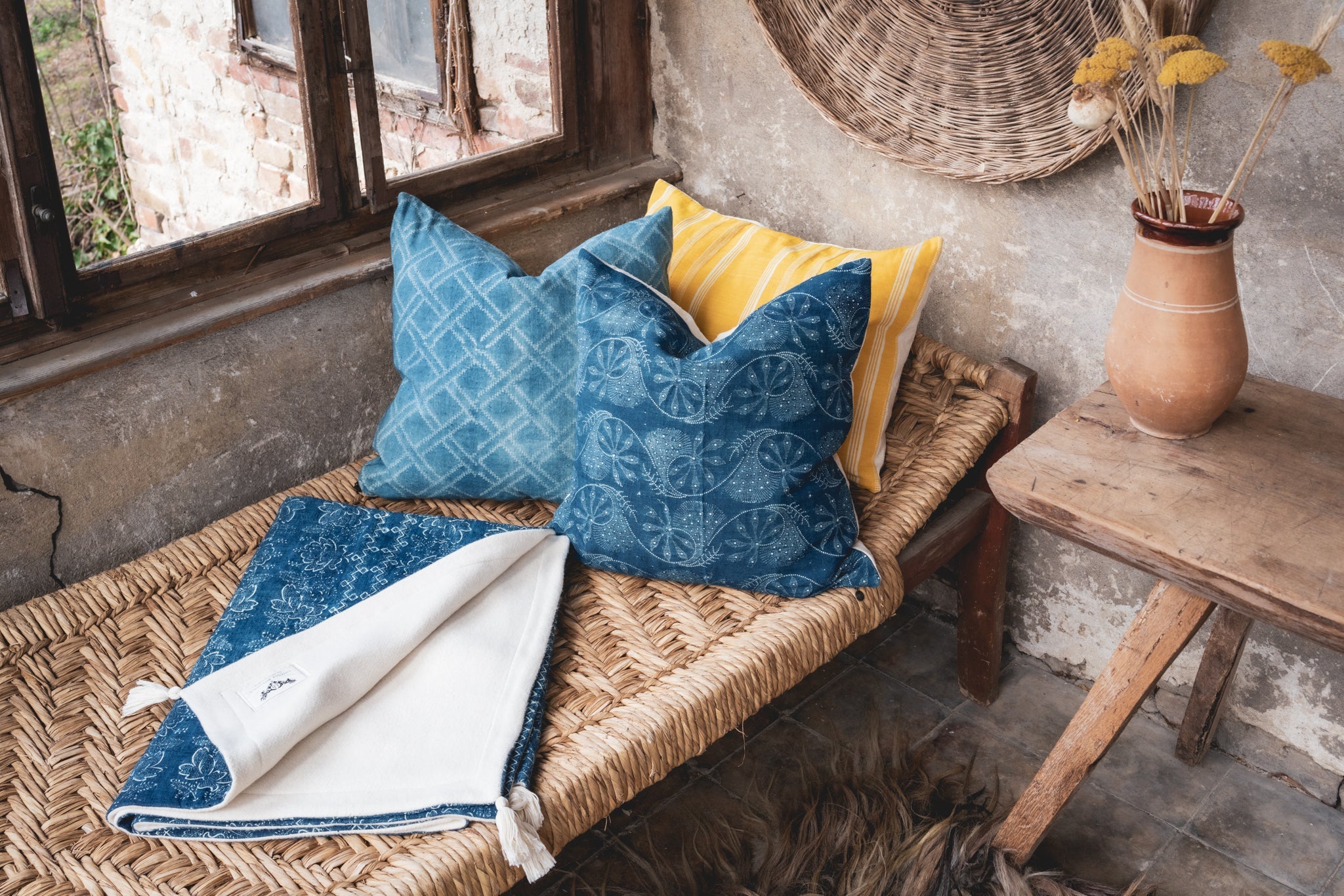 Handwoven antique Hungarian hemp pillow with wax resist indigo design on a rustic bench.