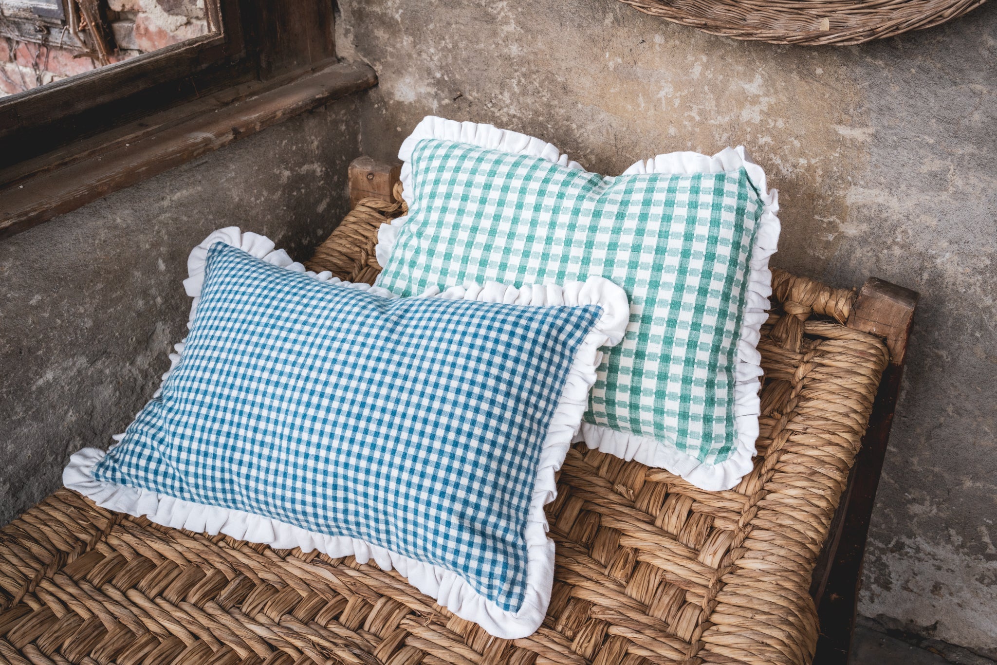 Antique handwoven decorative pillows with blue and green checks on a woven bench.