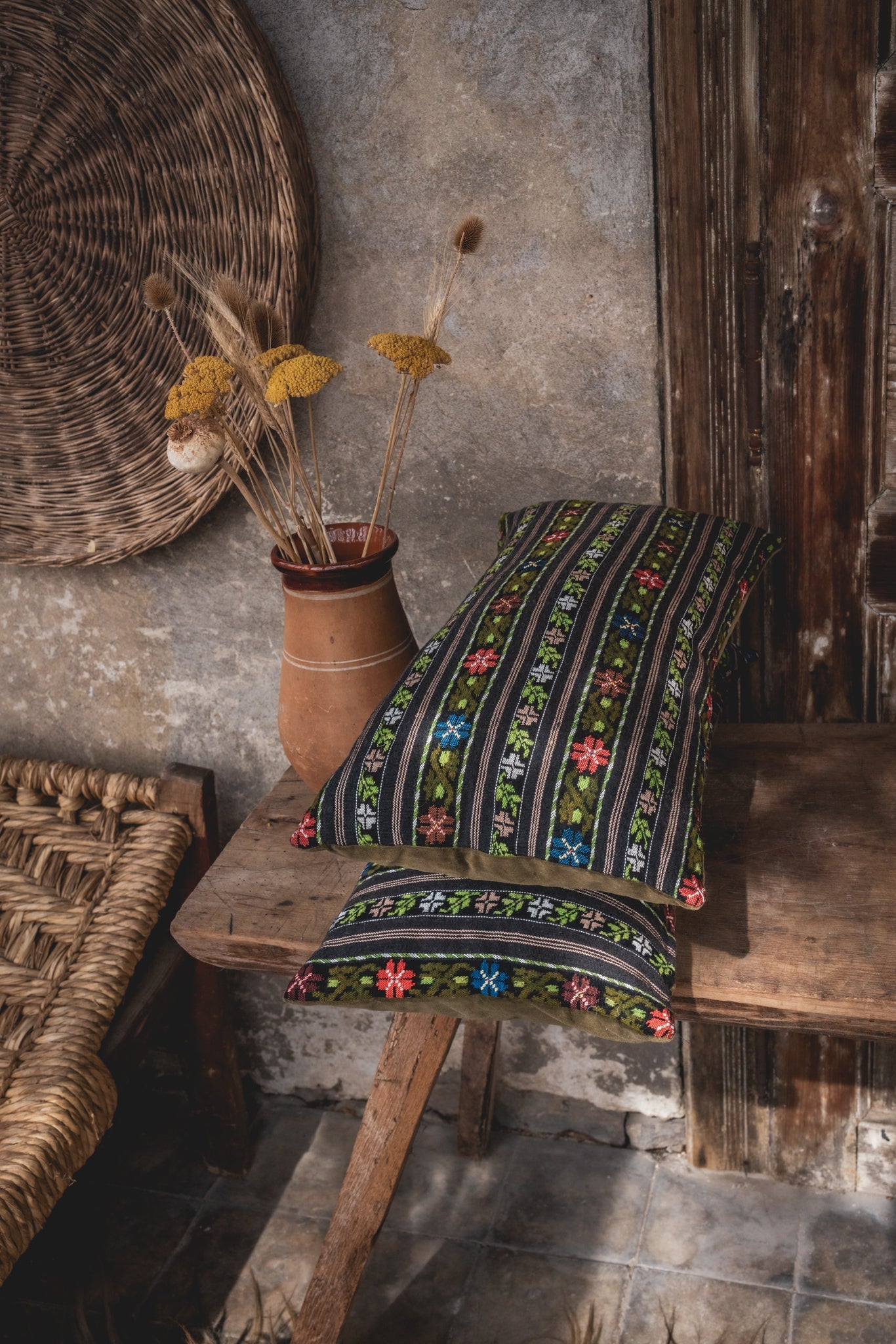 Handwoven Romanian artifact textile pillow with vibrant patterns displayed on rustic setting.