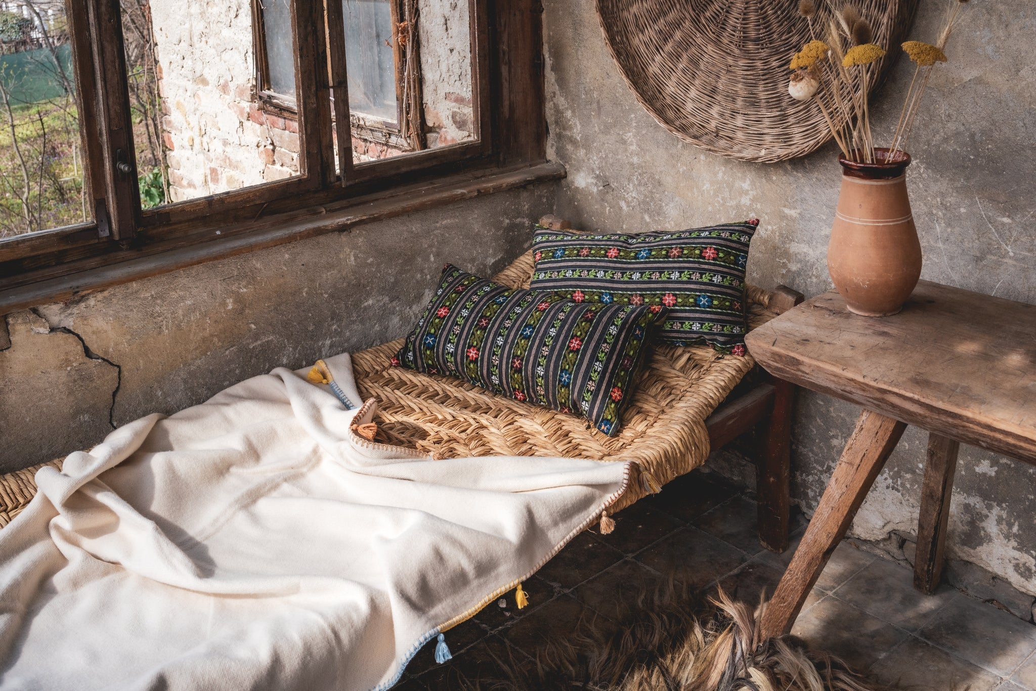 Artifact textile handwoven pillow on rustic Romanian bench with woven details and cotton velvet back.