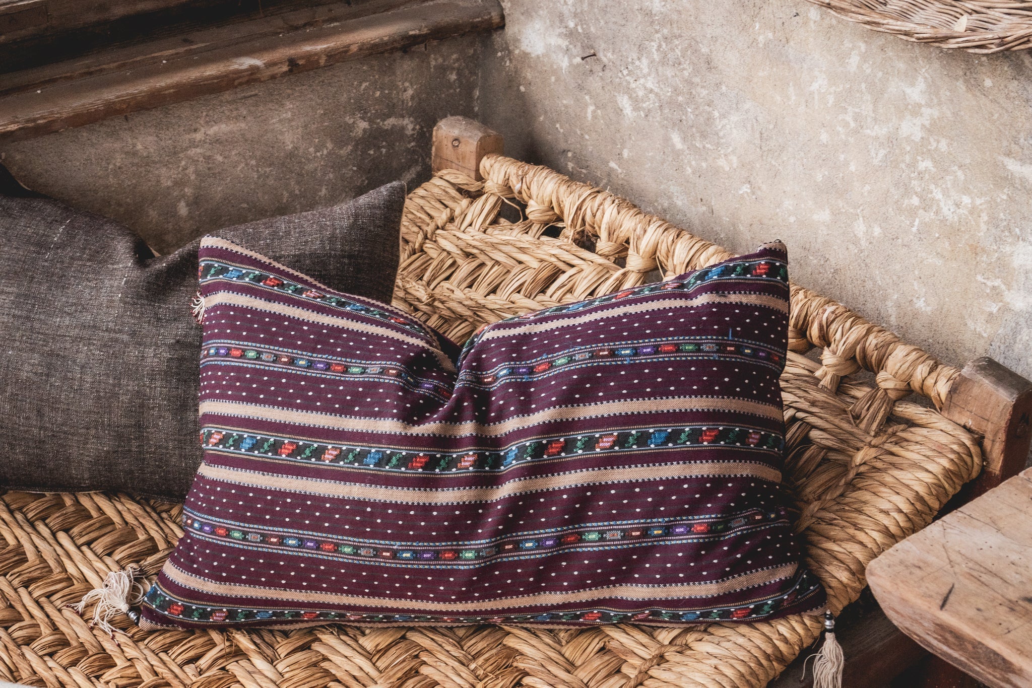 Handwoven Romanian artifact textile pillow on woven seat.