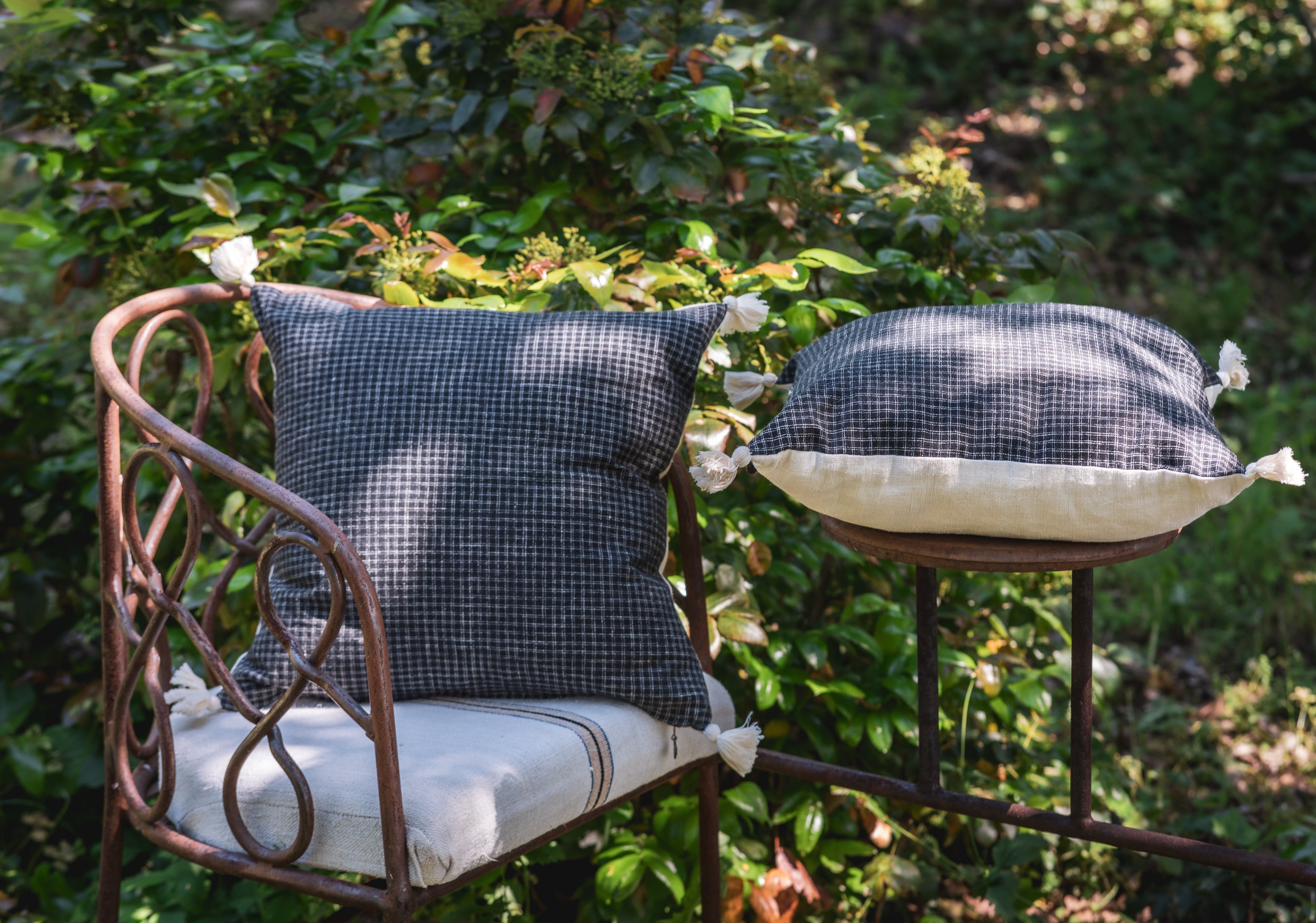 Antique handwoven decorative pillow with hemp back on rustic outdoor chair.