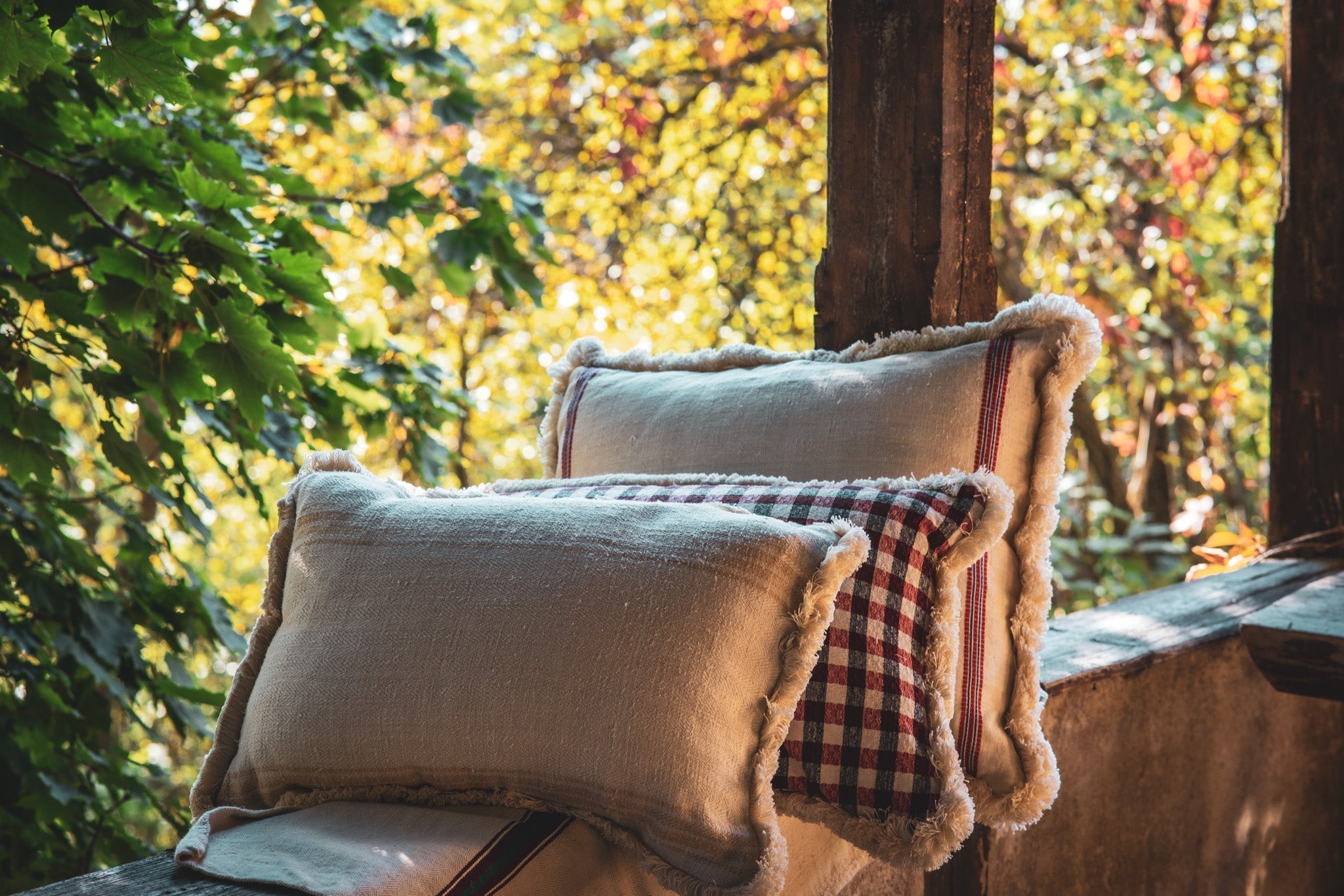 Embroidered antique handwoven Hungarian hemp pillows with fringe on outdoor bench.