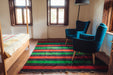 Antique handwoven Bulgarian rug with colorful stripes on a hardwood floor.