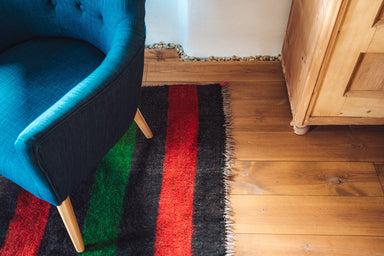 Antique handwoven Bulgarian felted rug with red, green, and black stripes.