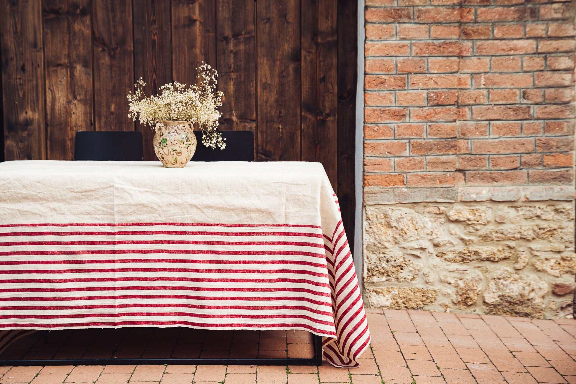 Antique handwoven hemp tablecloth with Bulgarian cotton border on outdoor table with floral centerpiece