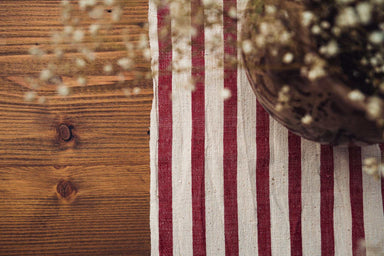 Antique handwoven hemp tablecloth with red and white stripes on wooden table with dried flowers